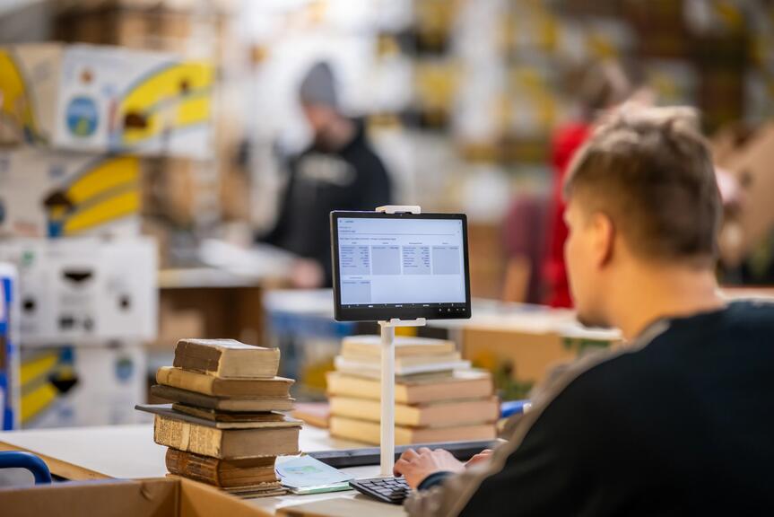 Henkilö lajittelee kirjoja.