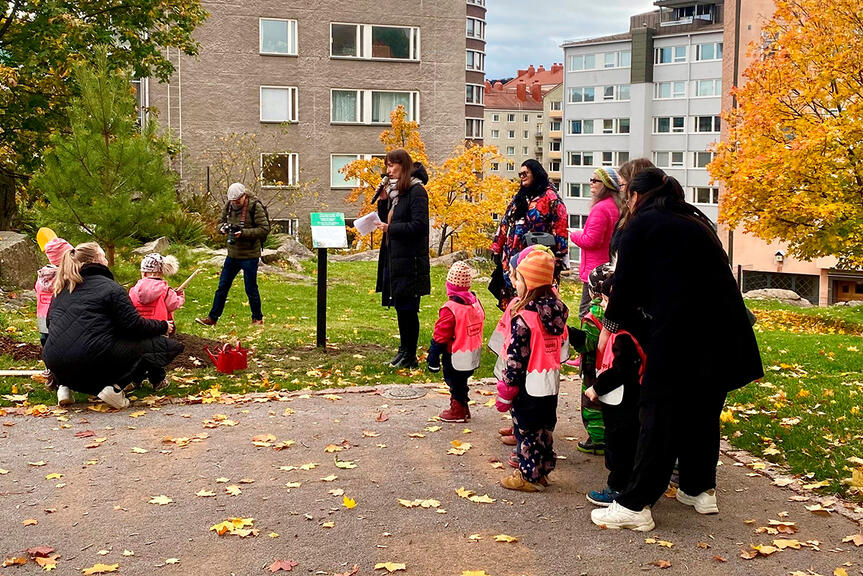 Lapset istuttamassa Lasten puuta Eveliina Heinäluoman pitäessä puhetta.
