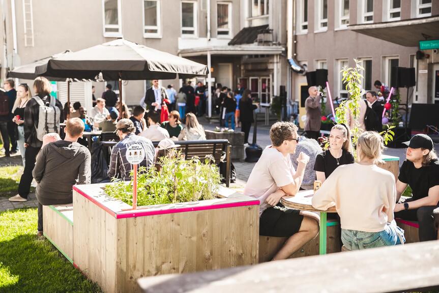 Kuvassa ihmisiä auringonpaisteessa Maria 01:n pihalla.