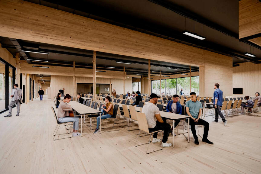 Nuoria ihmisiä istumassa avoimessa ja modernissa puunvärisessä huoneessa.