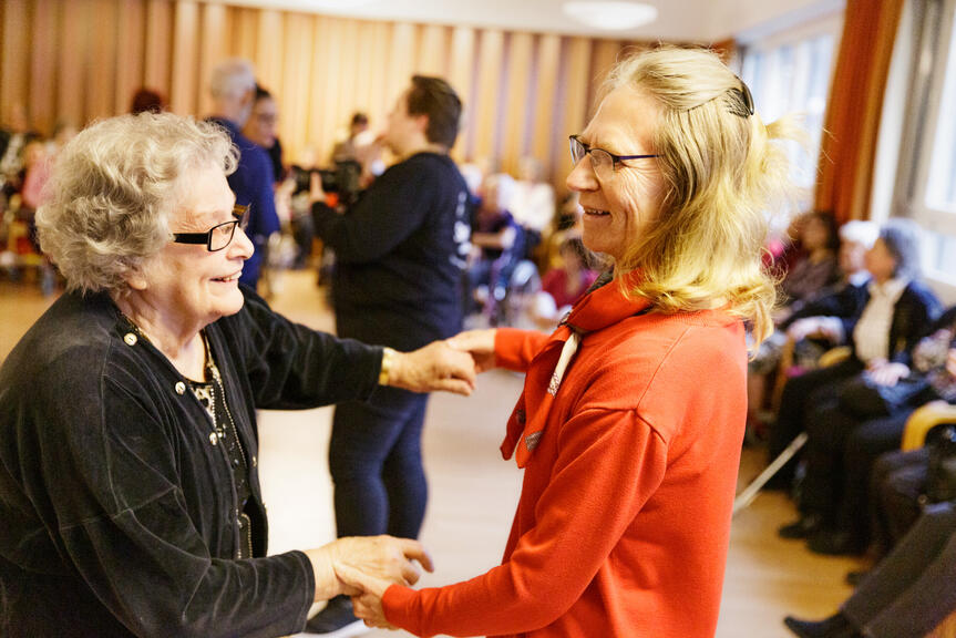 Iloiset ihmiset tanssivat seniori-ikäisille suunnatussa diskossa.