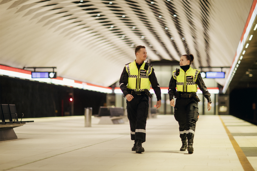 Kaksi Palmian turvallisuuspalveluihin kuuluvaa järjestyksenvalvojaa vartijaa kävelevät metrolaiturilla.