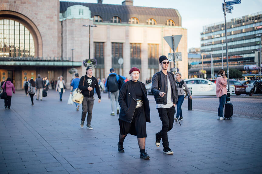 Kaksi henkilöä kävelee rautatieaseman edustalla.