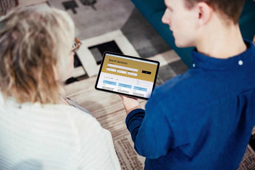 Two persons look at the home page of the Decisions service from a tablet computer.