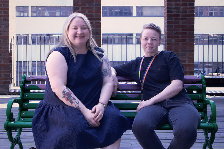 Two person are sitting on a bench.