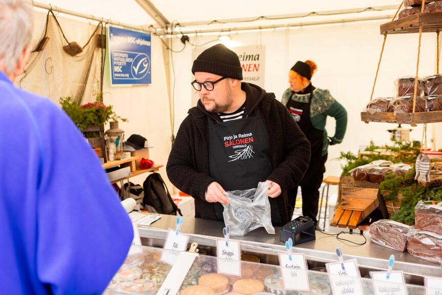 A salesperson wearing a black beanie behind the fish counter.