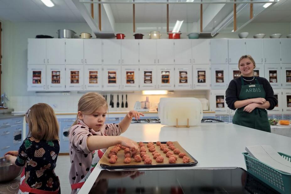 Ett barn rullar köttbullar.