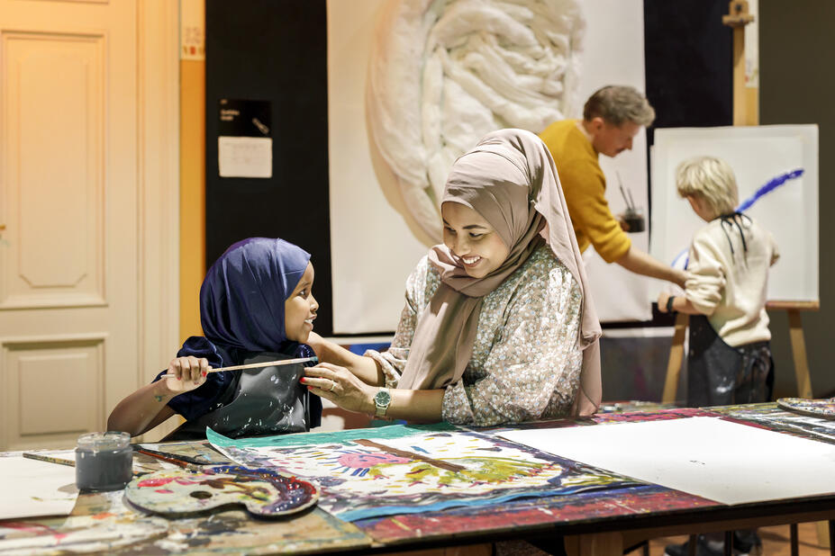 A child and an adult painting together.