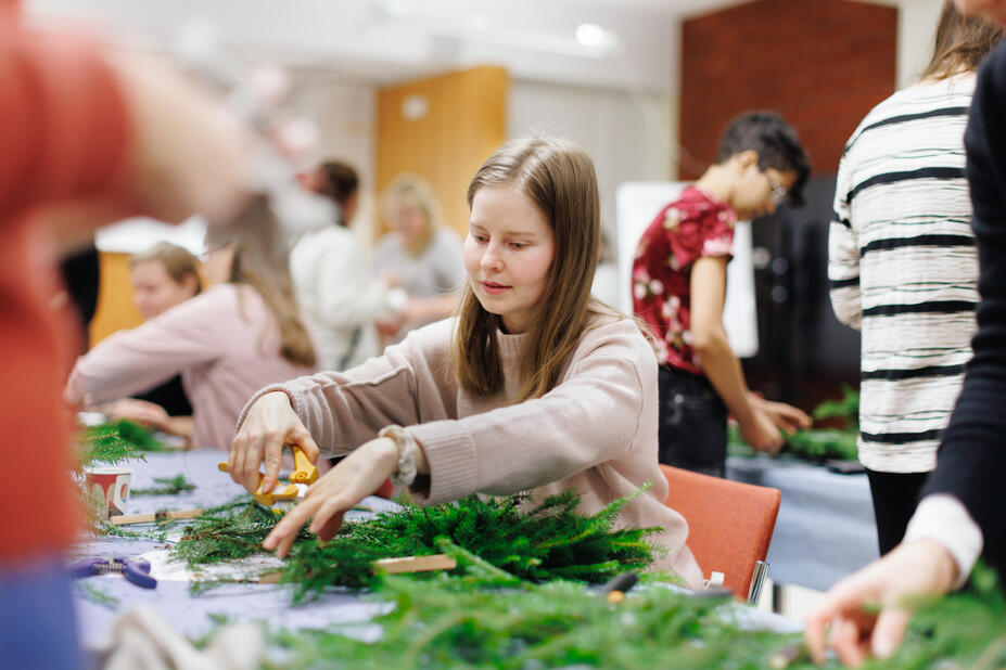Henkilö askartelee joulukranssia.