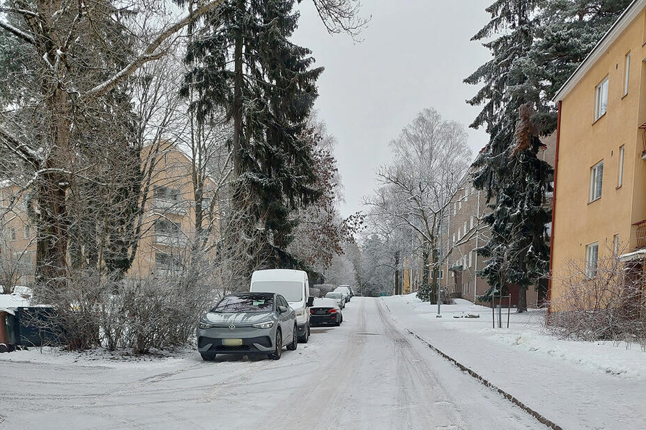 Katu, jolla on aurattu jalkakäytävä ja autoja pysäköitynä kadun toisella laidalla.