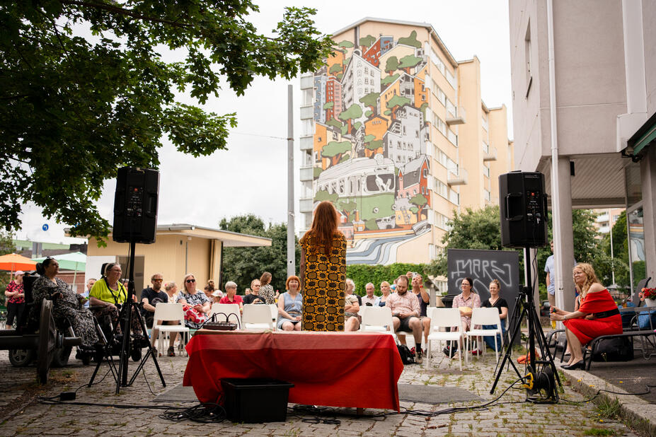 Esitys lippakioskilla, yleisö seuraa.