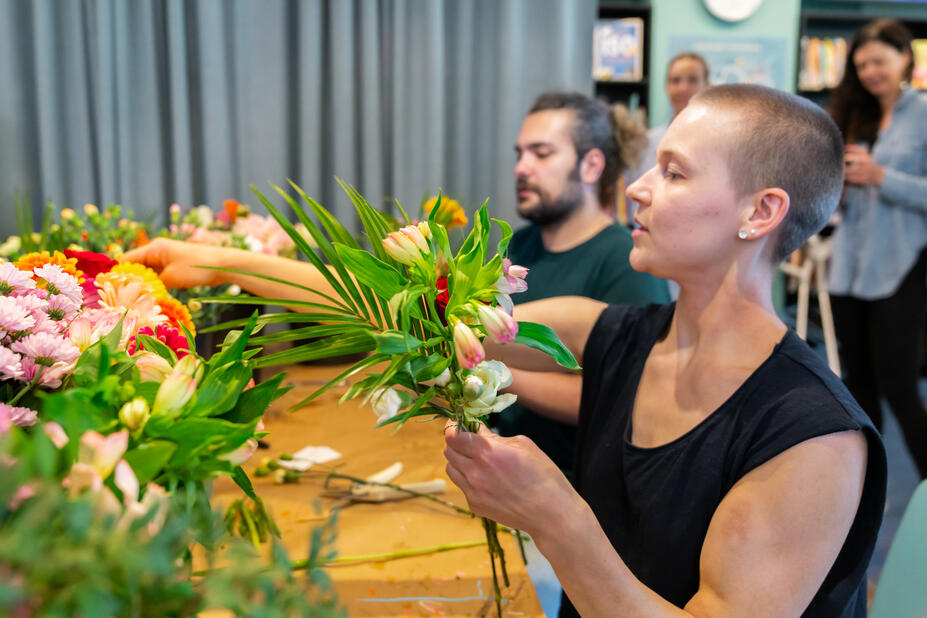 Kaksi ihmistä tekemässä kukkakimppuja.