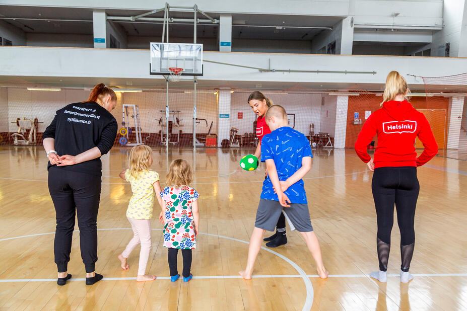 Adults and children in a sports hall.