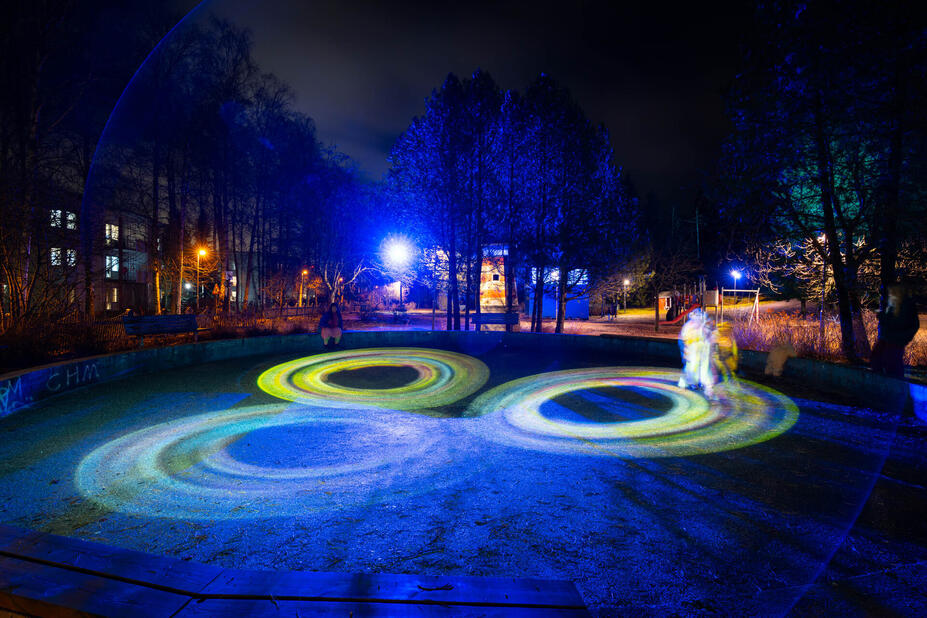 Pimeässä illassa otettu kuva, jossa valorenkaita ja ihmisiä.