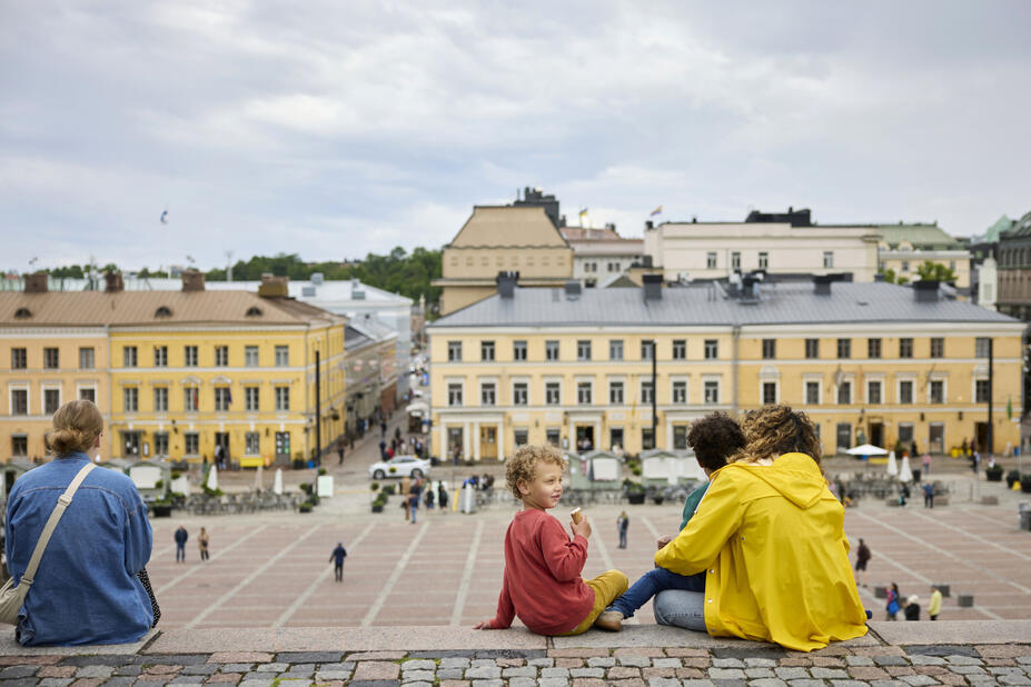 Ihmisiä istumassa Tuomiokirkon portailla, taustalla Senaatintoria.