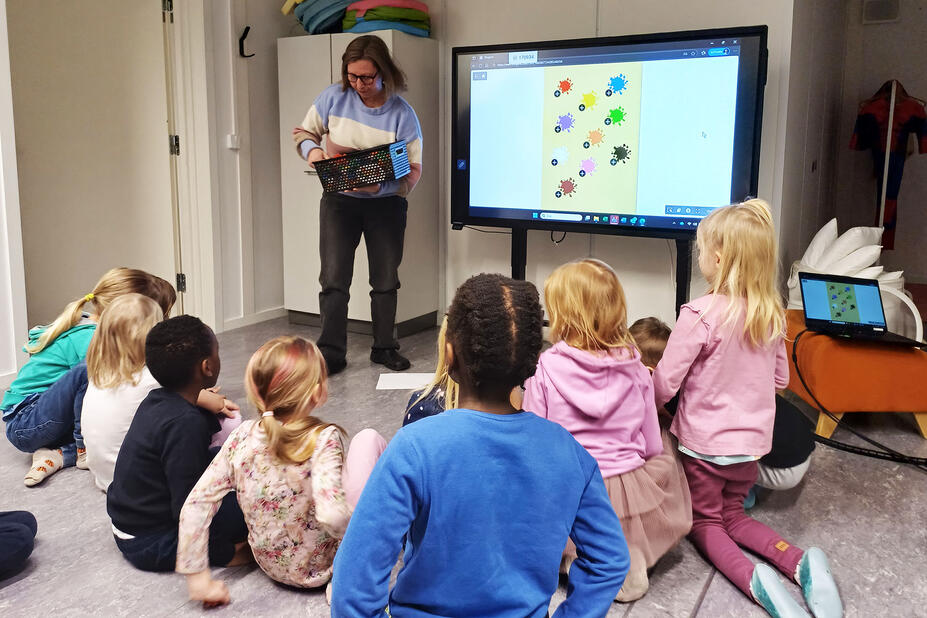 Opettaja kaivaa korista palikoita lasten edessä.