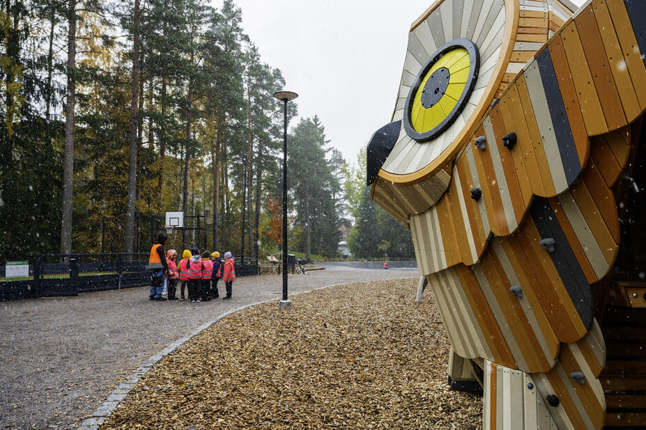 Syksyisessä puistossa lapsia ja pöllöliukumäki