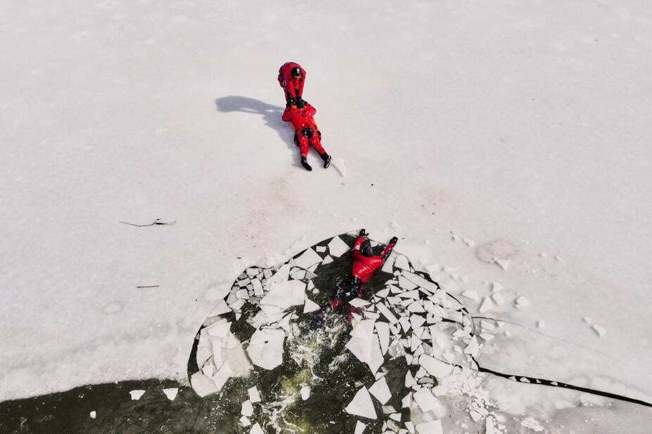 Kolme pelastajaa harjoittelevat jäihin pudonneen pelastamista.