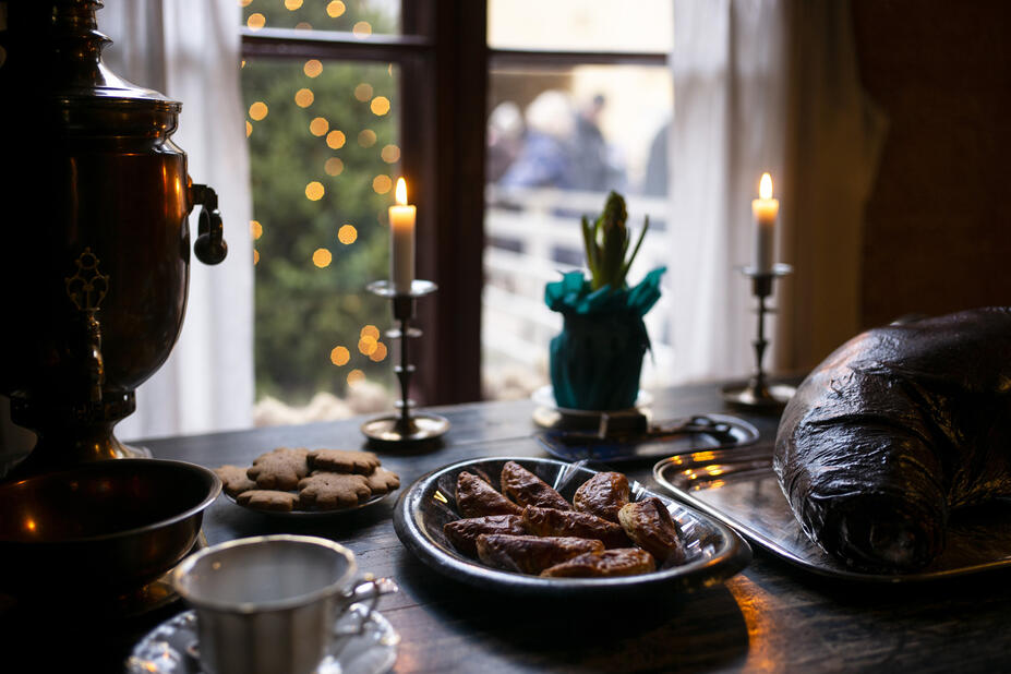 Pöydälle on aseteltu jouluista ruokaa sekä kynttilä. Ikkunasta on näkymä joulukuusen.