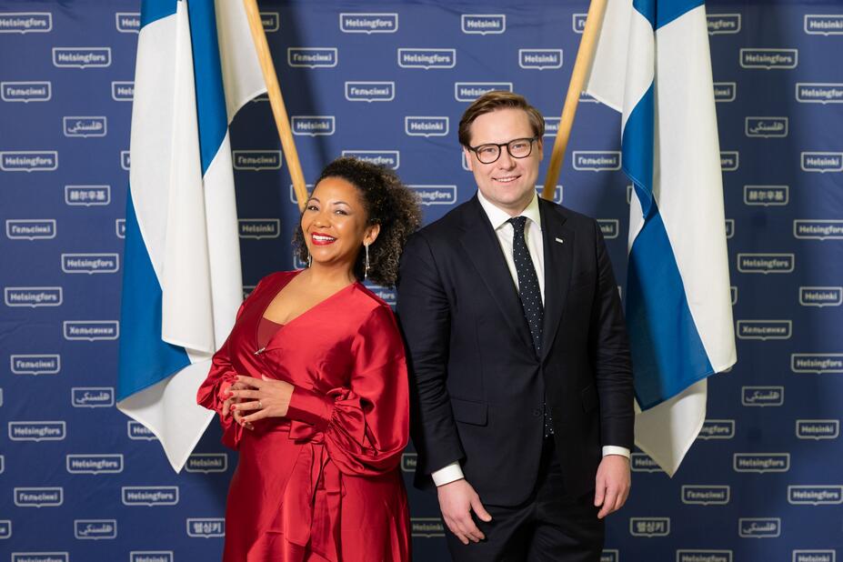 Mayor and Luciana Paltila in front of two Finnish flags.