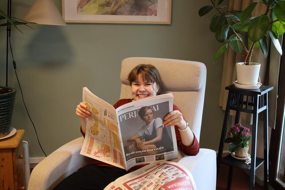 Tuuli, employed with pay subsidy, reading a newspaper in the living room of the Kehäkukka group home.