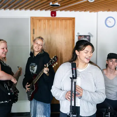 Young people in a band rehearsal place playing music.