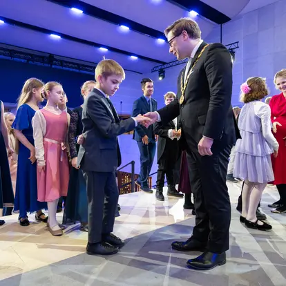 A boy shakes hands with the Mayor.