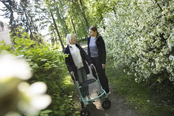Två personer står på gården. Den ena har en rollator.