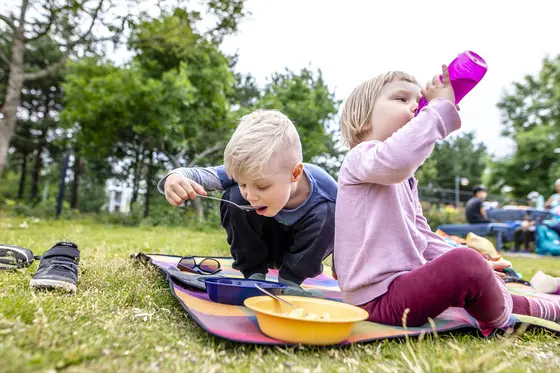 Two kids have lunch at the playground.