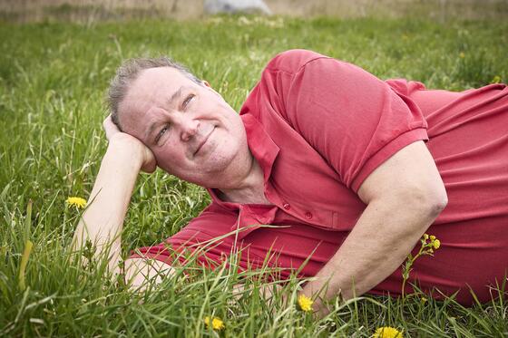 Lassi Jalonen is lying on a grassy meadow.