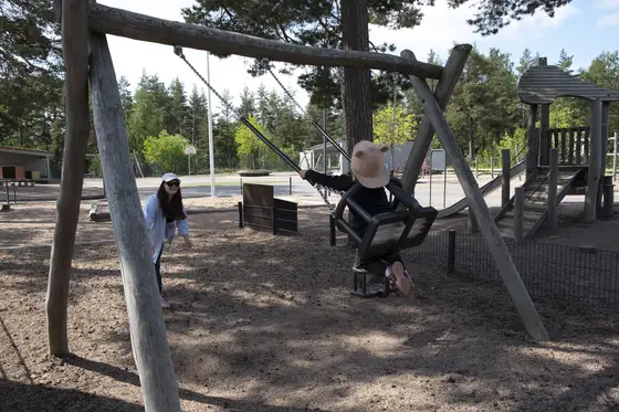 Lapsi keinuu ja aikuinen antaa vauhtia.
