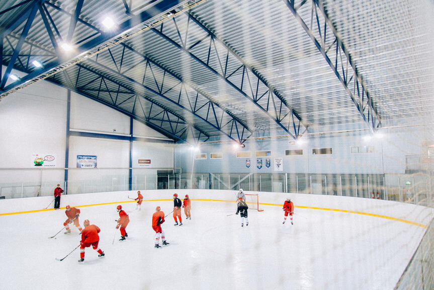 Red-clad players in a hockey game in an ice rink.