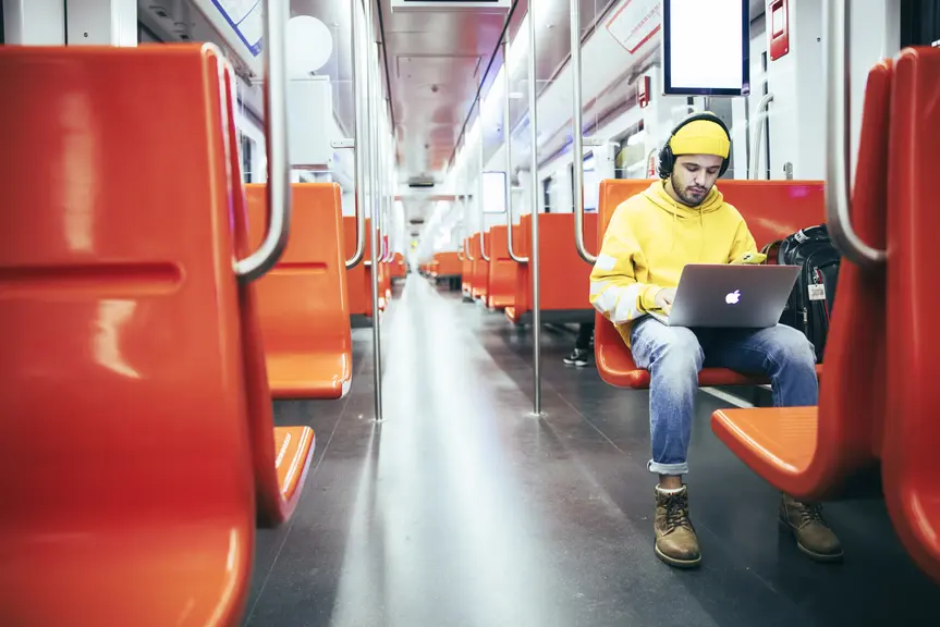 Mies käyttää läppäriä metrossa. 