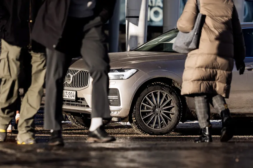 Jalankulkijoita ja pysäköity auto.