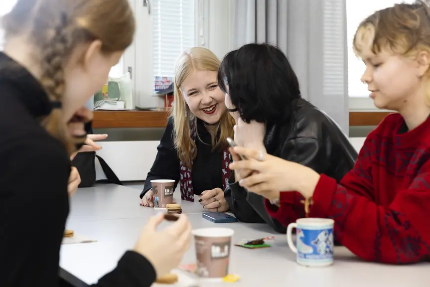Nuoria pöydän ääressä juomassa kahvia.