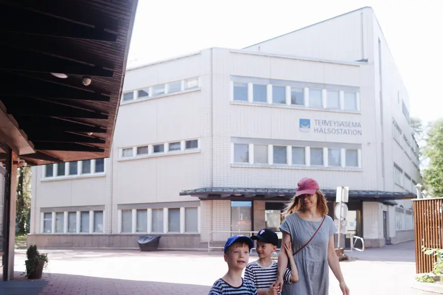 A mother and her children are walking in the health center yard.