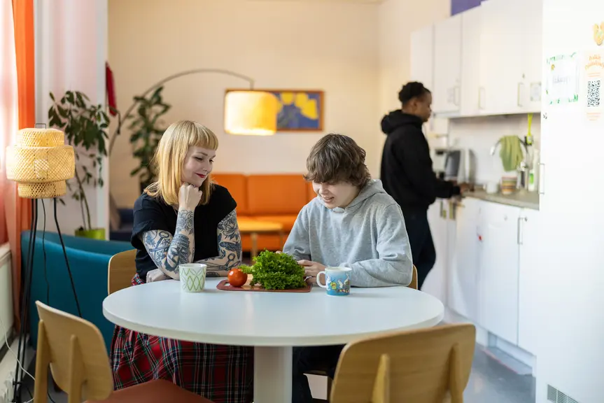 Työntekijä juttelee nuoren kanssa pöydän ääressä.