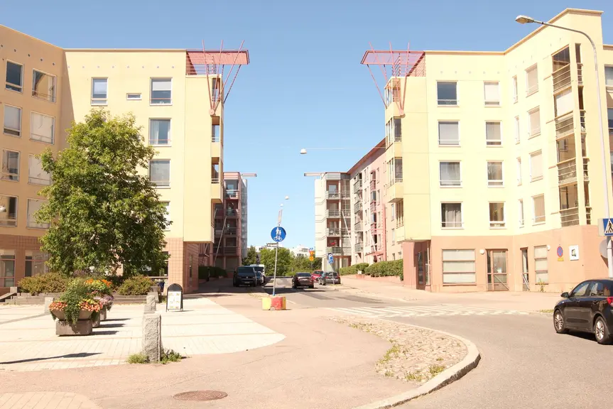 Aukio vaaleankeltaisten kerrostalojen edessä.