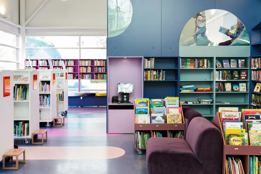 Blue-toned bookshelves and a reading loft in Pikku Huopalahti Library's main hall.