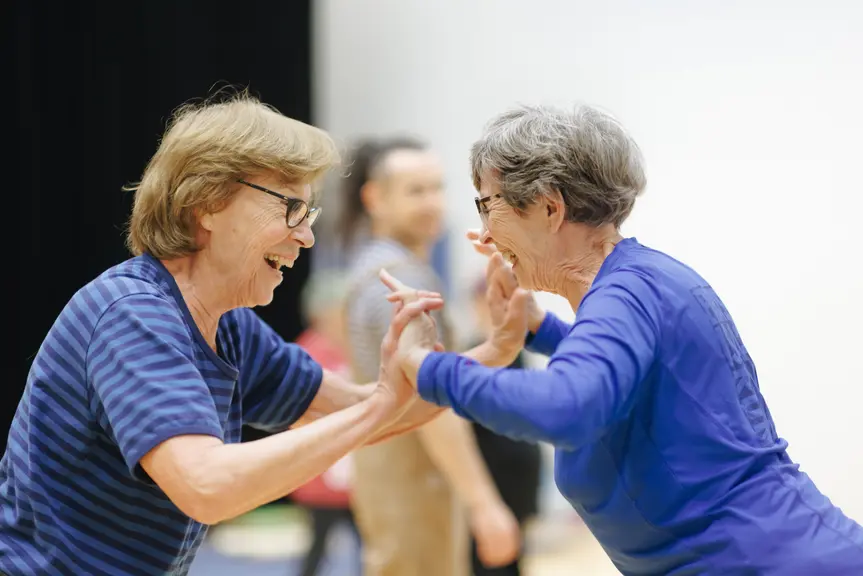 Two older people are smiling and holding hands. 