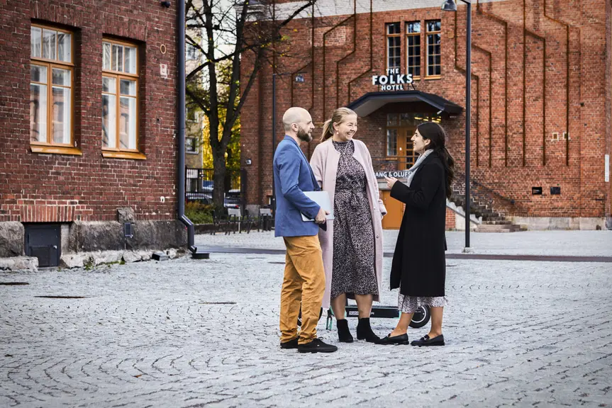 Kaksi naista ja mies seisovat keskustelemassa Konepajan alueella Vallilassa