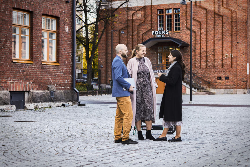 Kaksi naista ja mies seisovat keskustelemassa Konepajan alueella Vallilassa