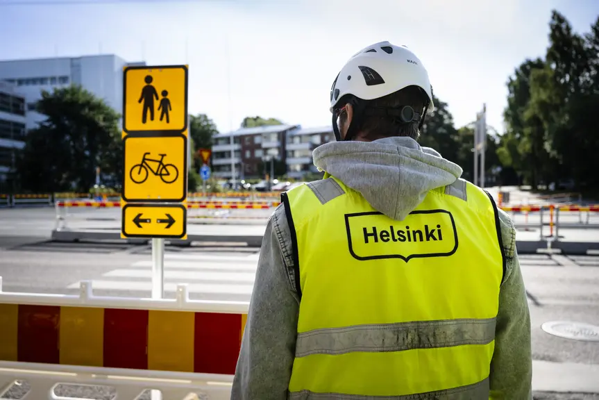 Helsinki-liiviin pukeutunut ihminen seisoo Länsiratikan työmaan edustalla