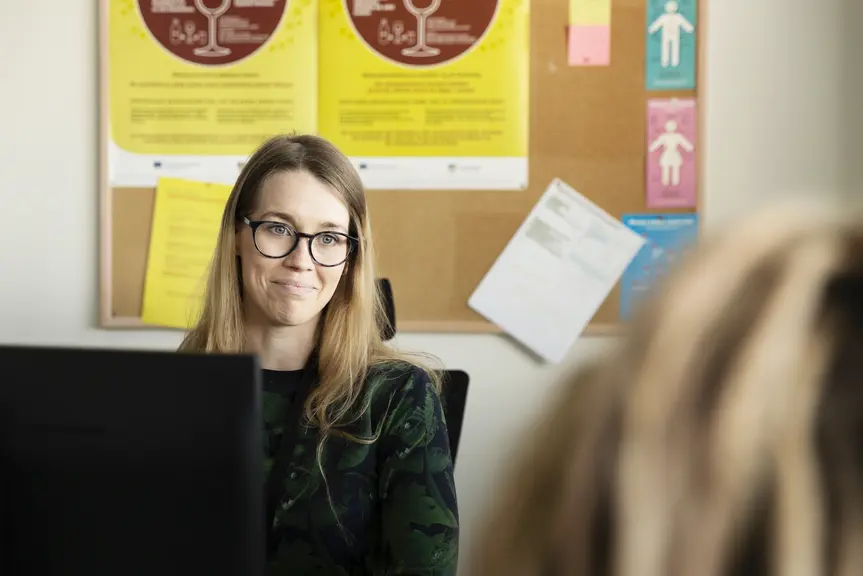 A person talks with a customer at a workstation.