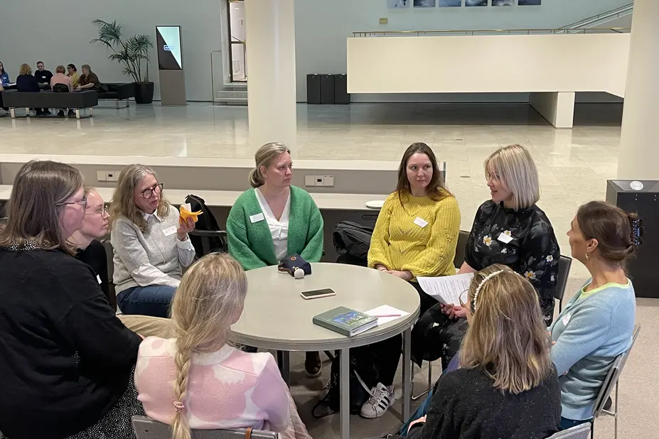 En grupp människor sitter runt ett bord och diskuterar.