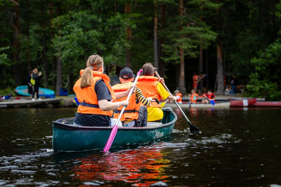 Unga människor paddlar på en sjö.