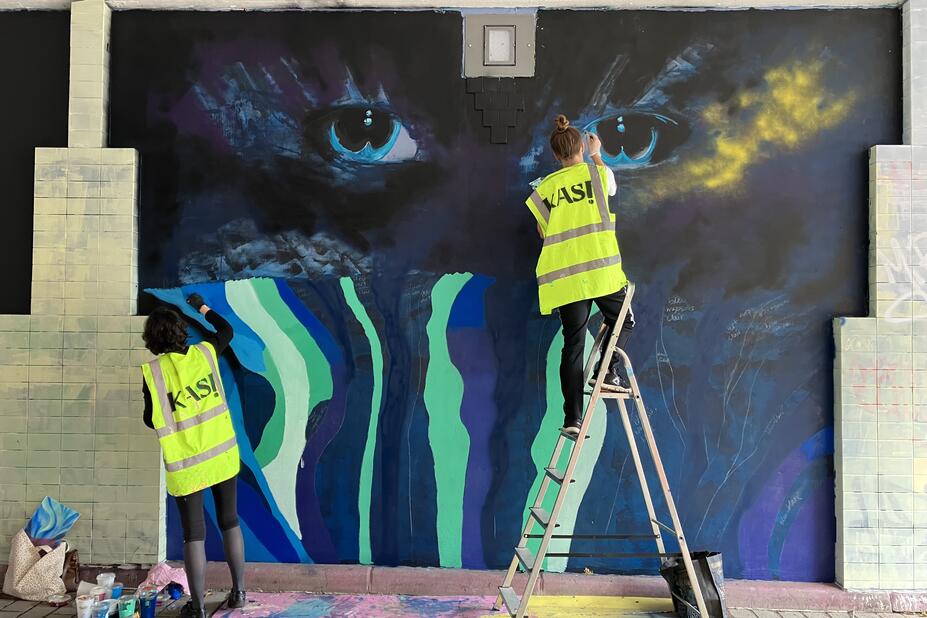 Two people painting street art.