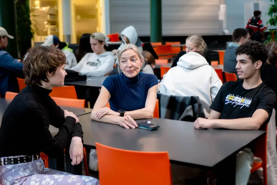 Hux-koordinatorn Sonja Andersson diskuterar med studerandena Sami Kordander och Mohammed Sahib vid ett bord.