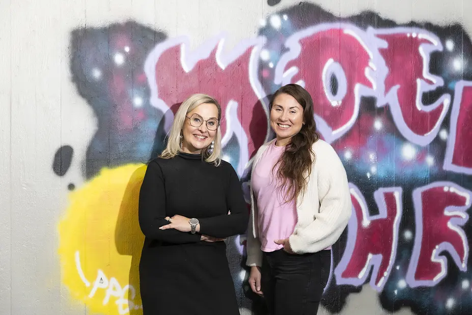 Jutta-Riina Karhunen ja Jenni-Pauliina Jokinen graffitin edessä