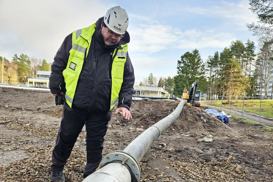 Työmaapäällikkö työmaalla katsoo maassa olevaa putkea.